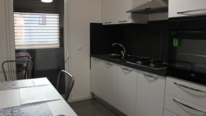 A compact kitchen with white cabinets, a black countertop, a sink, and a built-in oven. - B&B Al Porticciolo (Marsala)