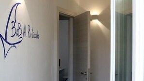 A hallway with a sign reading "BB Al Portico" and a glass door leading to another room. - B&B Al Porticciolo (Marsala)