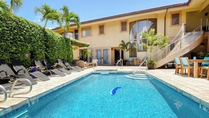 A swimming pool with lounge chairs and a staircase leading to an upper level. - Aloha Villas # 2, Steps to Beach, Close to Golf & (Kihei)