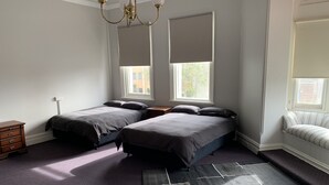 A bedroom with two beds, a dresser, a rug, and a window with blinds. - Leura Hotel Camperdown (Camperdown)