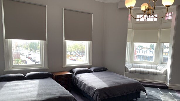 A hotel room with two beds, a bench by the window, and a chandelier. - Leura Hotel Camperdown (Camperdown)
