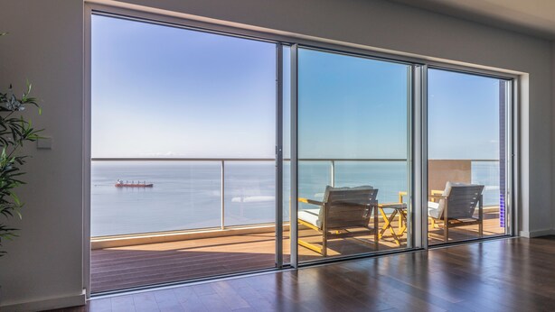 A spacious balcony with a clear view of the sea and a ship in the distance. - Xenon urban apartments (Maputo)