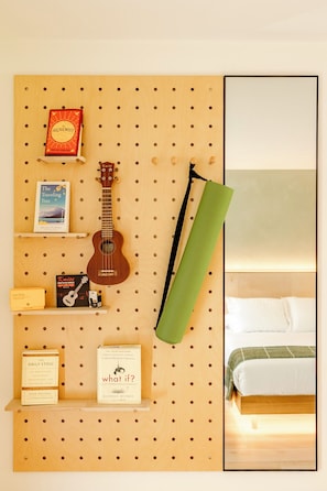 A wall-mounted pegboard with books, a ukulele, and a green towel. - Otherland Hotel (Newfane)