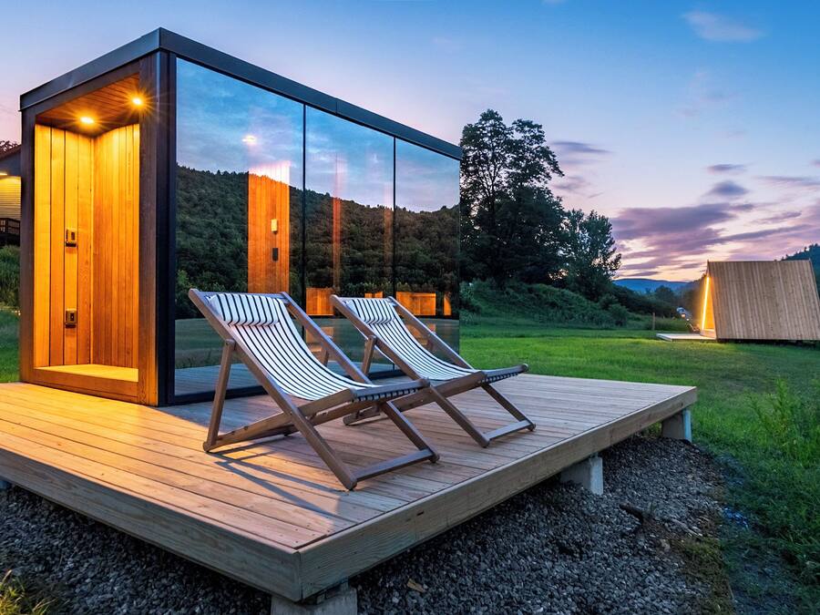Uma área de estar moderna ao ar livre, com duas poltronas e um deck de madeira.