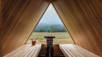 Interior de madera con vista a un bosque a través de una abertura triangular.