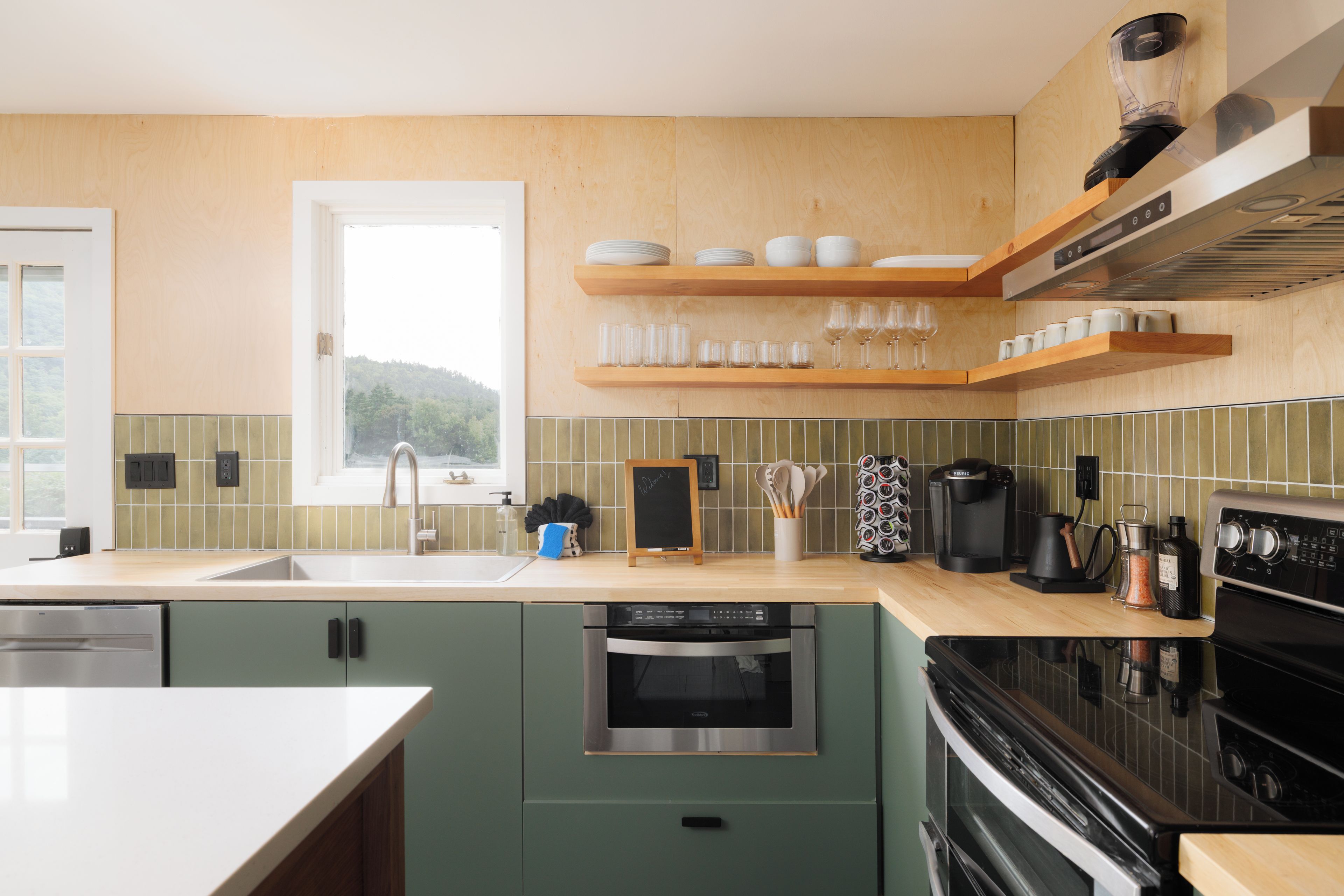 Een moderne keuken met houten kastjes, een RVS vaatwasser, een zwarte oven en een koffiezetapparaat.