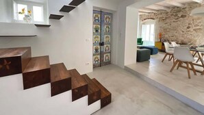 A modern interior with a staircase, a dining area, and a stone wall. - Ortigia Luxury Apartment w/ Sea View & Terraces (Syracuse)