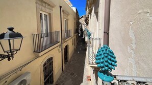 A narrow street with buildings on either side, featuring balconies with railings and a street lamp. - Ortigia Luxury Apartment w/ Sea View & Terraces (Syracuse)