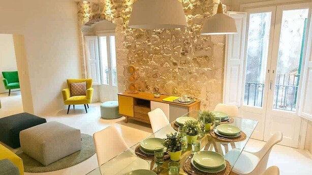 A dining area with a glass table set for four, surrounded by white chairs. - Ortigia Luxury Apartment w/ Sea View & Terraces (Syracuse)