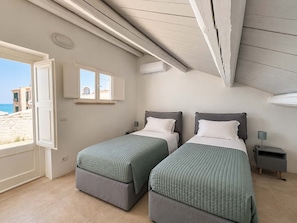 Ein Schlafzimmer mit zwei Betten, einem Fenster und einer Klimaanlage.
