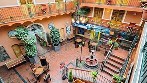 A spacious indoor courtyard with multiple seating areas, potted plants, and a central fountain.