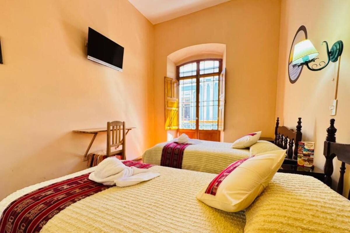 Een hotelkamer met twee bedden, een televisie, een raam met uitzicht en een lamp.