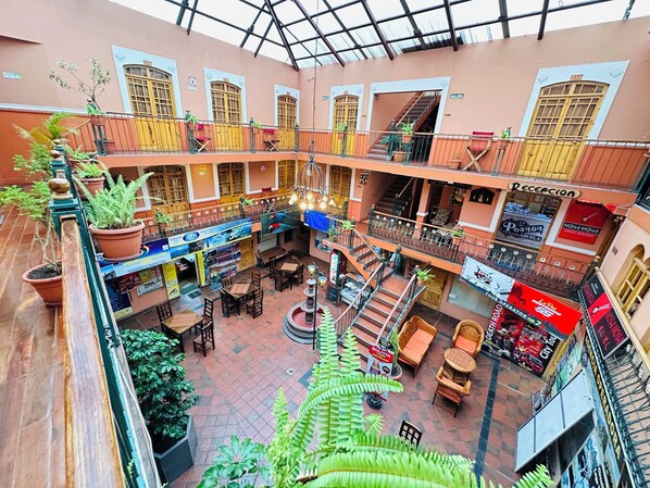 A multi-level atrium with a central staircase, potted plants, and various seating areas. - La Posada de la Abuela Obdulia (La Paz)