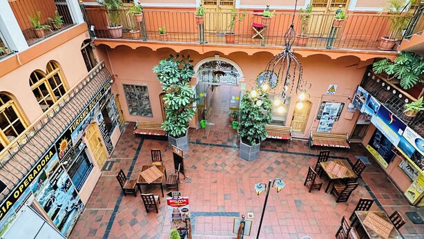 A multi-level atrium with a central staircase, potted plants, and outdoor seating areas.