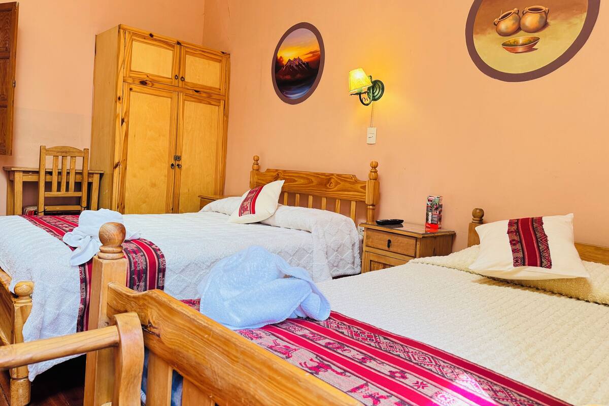 Een slaapkamer met twee bedden, een houten garderobe, een stoel, een nachtkastje en een wandlamp.
