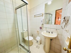 A bathroom with a glass-enclosed shower, a sink, a toilet, and a hairdryer mounted on the wall. - La Posada de la Abuela Obdulia (La Paz)