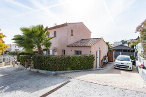 A two-story house with a tiled roof, a white car parked in the driveway, and a palm tree in the front yard. - Fully equipped villa with SPA near Nice (Cagnes-Sur-Mer)