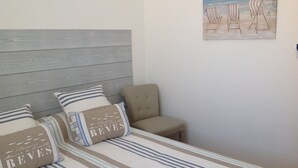 A bed with striped bedding and pillows, a grey headboard, and a beach-themed painting on the wall. - Four-room apartment Saint Cyr sur Mer La Madrague sea view in guarded residence (Saint-Cyr-Sur-Mer)