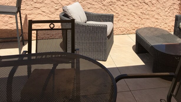 A patio with wicker furniture, a round table, and a view of a beach and cityscape. - Four-room apartment Saint Cyr sur Mer La Madrague sea view in guarded residence (Saint-Cyr-Sur-Mer)