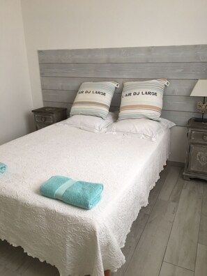 A neatly made bed with a white bedspread and two pillows with striped patterns.