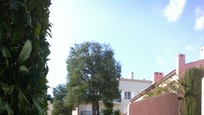 A paved pathway leading to a building with a stone wall and a tree in the center. - Four-room apartment Saint Cyr sur Mer La Madrague sea view in guarded residence (Saint-Cyr-Sur-Mer)