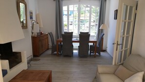 A living room with a sofa, a wooden coffee table, a dining table with chairs, a fireplace, and a large window with curtains. - Four-room apartment Saint Cyr sur Mer La Madrague sea view in guarded residence (Saint-Cyr-Sur-Mer)