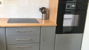 A kitchen with grey cabinets, a wooden countertop, a stainless steel range hood, and a black oven. - Four-room apartment Saint Cyr sur Mer La Madrague sea view in guarded residence (Saint-Cyr-Sur-Mer)