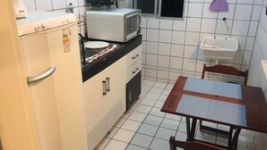 Cuina compacta amb nevera, microones, rentapelats i taula petita amb caires.
