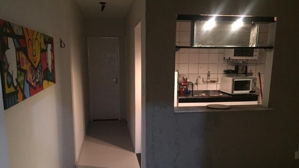 Passadís estret que condueix a una cuina amb microones i una petita illa.