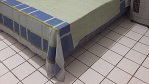 Habitació petita amb un llit individual, una colcha verd i blava, un radiador blanc i una cortina a la finestra.