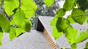 Une cabane en rondins avec une façade en bois, une véranda dotée d’une balustrade et une porte surmontée d’une fenêtre.