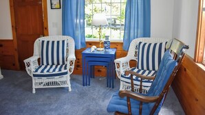Une pièce comprenant deux fauteuils en osier à rayures bleues et blanches, une petite table bleue et une chaise en bois.