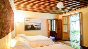 Un dormitorio con dos camas, techo de madera, un cuadro en la pared y vistas al balcón exterior.