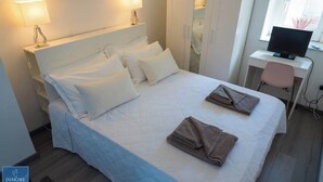 Een hotelkamer met een bed, nachtlampjes, een bureau met een computer en een stoel.