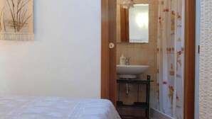 A bedroom with a bed, a bathroom with a sink and mirror, and a shower curtain. - Agriturismo La Petrosa - Granaio Woe (Petrosa)