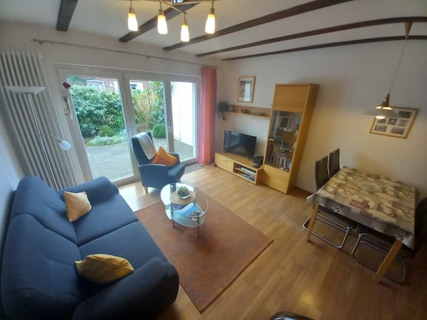 Un salon comprenant un canapé, un fauteuil, une table basse, un téléviseur et un coin repas avec une table et des chaises.