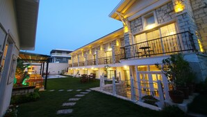 A multi-story hotel with a stone facade, outdoor seating area, and a well-lit entrance. - Duman Boutique Hotel (Cesme)