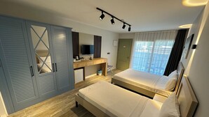 Ein Schlafzimmer mit Bett, Schreibtisch, Kleiderschrank, Fernseher und einem Fenster mit Vorhängen.