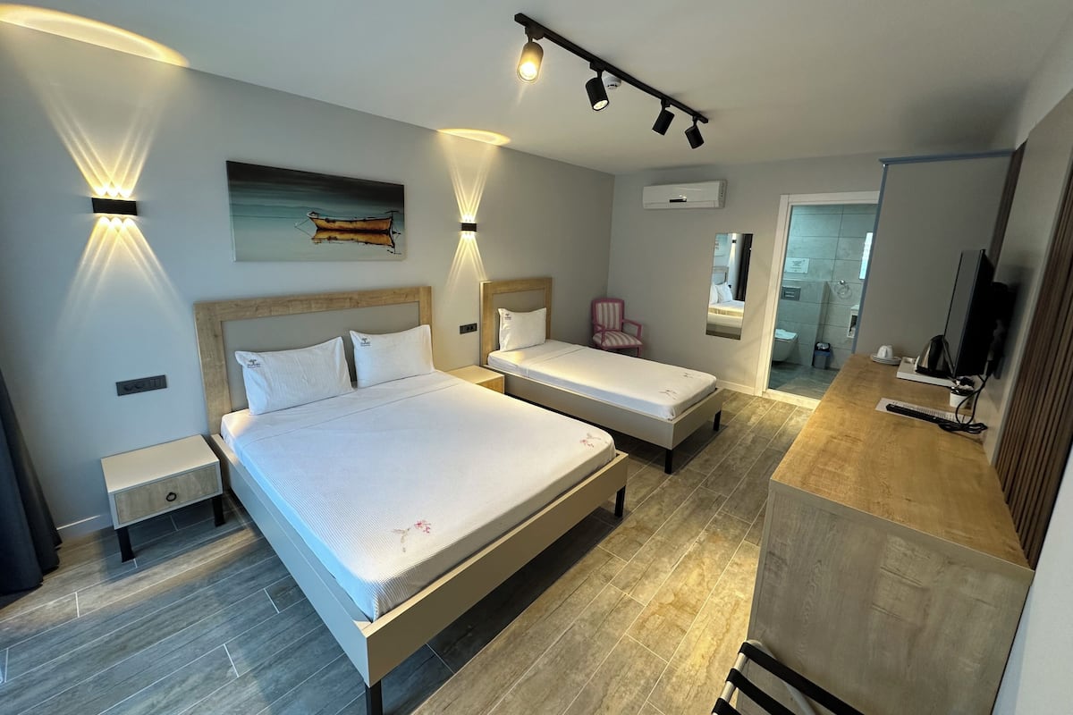 Une chambre d’hôtel moderne avec deux lits, un petit bureau, une chaise et un miroir.