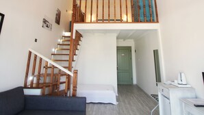 A multi-level living space with a staircase, a chandelier, a green door, and a small kitchenette. - Duman Boutique Hotel (Cesme)