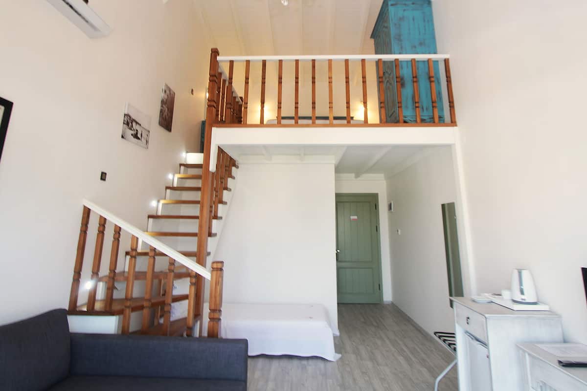 Un espace de vie à plusieurs niveaux comprenant un escalier, un lustre, une porte verte et une petite cuisine.