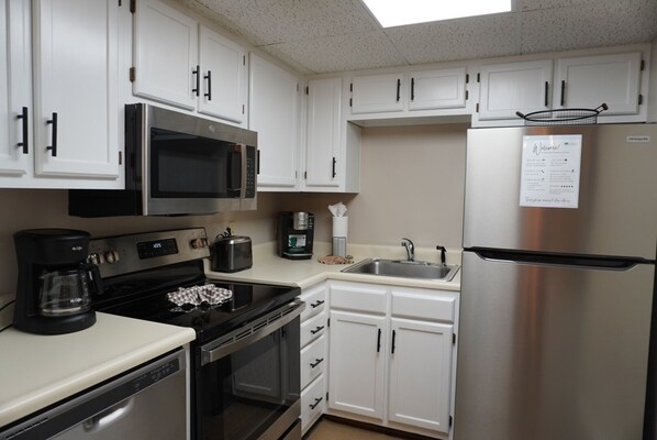 A kitchen with white cabinets, a stainless steel refrigerator, a microwave, a coffee maker, and a toaster. - Little Pigeon River 401 2BD Condo with Jacuzzi Tub (PIGEON FORGE)