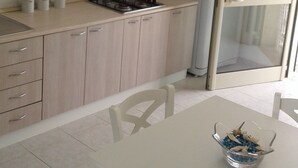 Una cucina moderna con mobili chiari in legno, un fornello a gas e un frigorifero.