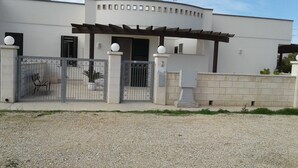 Un edificio moderno con ingresso chiuso da cancello, un portico coperto e un muro in pietra.