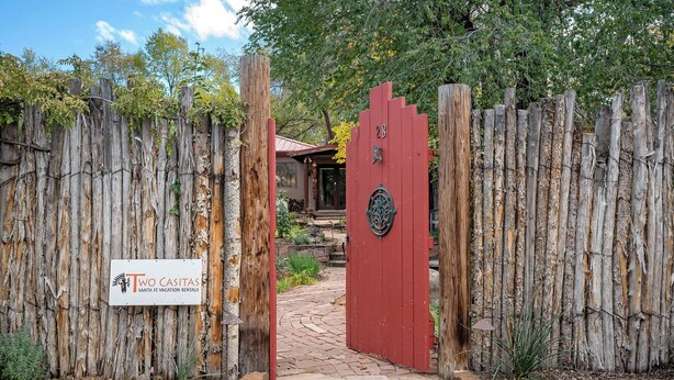 Ein rustikales Holztor mit einem Schild für 'Two Casitas Santa Fe Vacation Rentals'.