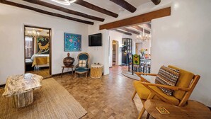Ein geräumiges Wohnzimmer mit freiliegenden Holzbalken, einem großen Holztisch und einer gemütlichen Sitzecke mit Sofa und Sesseln.