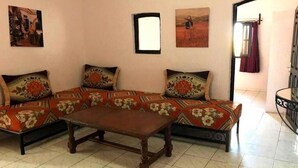 A living room with a sofa set, a coffee table, and two wall-mounted paintings. - Nardina Golden Residence 3921 (TETOUAN)