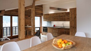 Een moderne keuken met houten kastjes en een eethoek met een houten tafel en witte stoelen.