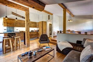 A spacious living area with a wooden coffee table, a sofa, and a kitchen in the background.
