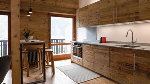 Een moderne keuken met houten kastjes, een inbouwoven en een groot raam.